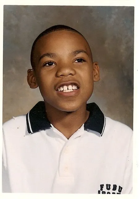 Deron Dalton, wearing a white and black FUBU shirt, smiles with his gap tooth for picture day during grade school in Grandview, Mo. in the late '90s.